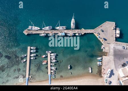 Kykladen Griechische Insel Hafen Marina Luftdrohne Draufsicht. IOS Insel, Griechenland, traditionelle Fischerboote und Yachten, die am Hafendock festgemacht sind, ruhiges blu Stockfoto