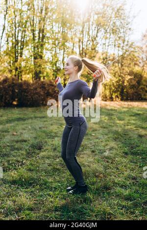 Hübsches, schlankes Mädchen, das im Freien auf einem Springseil springt Stockfoto