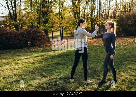 Fitness im Freien, zwei Mädchen halten die Hände, Gesicht zu einander. Stockfoto