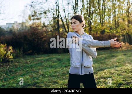 Junge Frau, die sich im Park ausdehnt und sich aufwärmt. Attraktive Mädchen Stretching vor Fitness. Schöne sportliche Mädchen tun Fitness im Freien. Stockfoto