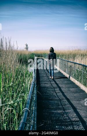 Frau auf einer Brücke in der Nähe eines Leuchtturms. Stockfoto