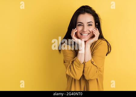 Lächelnde Brünette posiert wunderschön auf einem orangen Hintergrund. Platz für Text, Platz zum Kopieren. Stockfoto