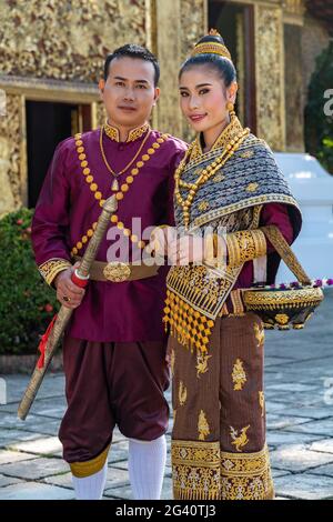 Glückliches Brautpaar in wunderschöner laotischer Hochzeitskleidung während des Fotoshootings im Wat Xieng Thong Tempel, Luang Prabang, Provinz Luang Prabang, Laos, Asi Stockfoto