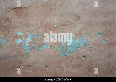 Eine alte Wand mit einer hellen, verblassten orangen Farbe und etwas abgefallenem Putz und abblätternder Farbe. Stockfoto