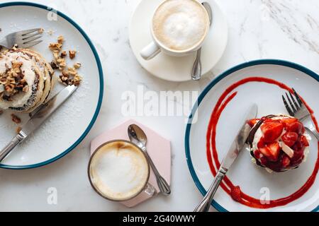 Pfannkuchen und Kaffee zum Frühstück in einem Café. Blick von oben - Frühstück mit Pfannkuchen und Kaffee auf dem Tisch Stockfoto