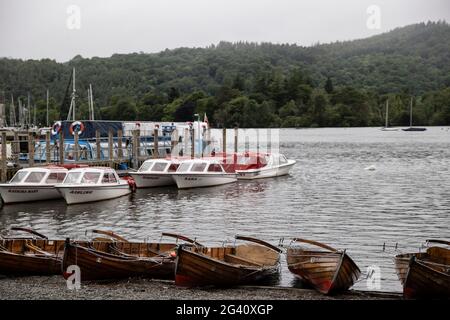 Windermere, Cumbria, England. 16. Juni 2021. Ruderboote zum Mieten sind neben einem Steg am Lake Windermere zu sehen. Stockfoto