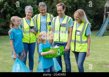 Lächelnd kaukasischen Multi-Generation männliche und weibliche Freiwilligengruppe sammeln Müll auf dem Feld Stockfoto