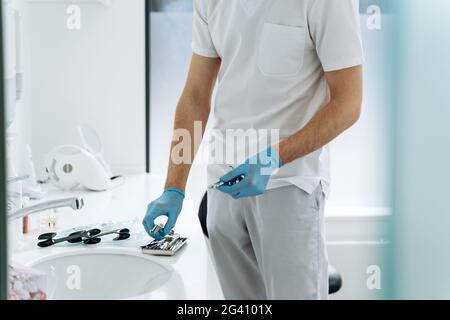 Nahaufnahme, junger Zahnarzt arbeitet mit Arbeitswerkzeugen im Büro. Ein hübscher, junger Mann bereitet sich auf die Arbeit vor Stockfoto