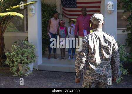 afroamerikanischer Soldat Vater vor Frau, Kinder und Vater begrüßen ihn vor dem Haus Stockfoto