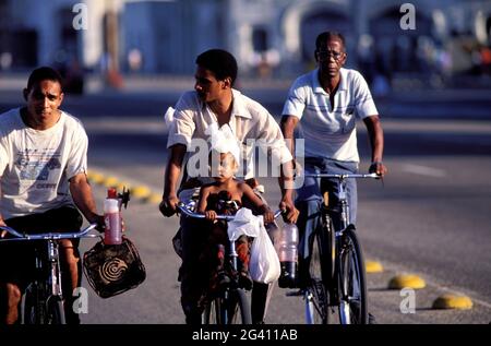 KUBA, HAVANNA, KUBANER DURCH DIE FAHRRÄDER AUF DEM MALECON BOULEVARD (AM MEER) Stockfoto