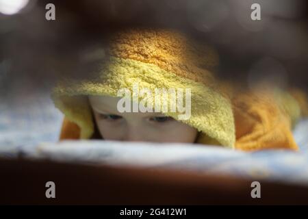 Der kleine Junge friert im Winter in warmen gelben Pyjamas ein Stockfoto