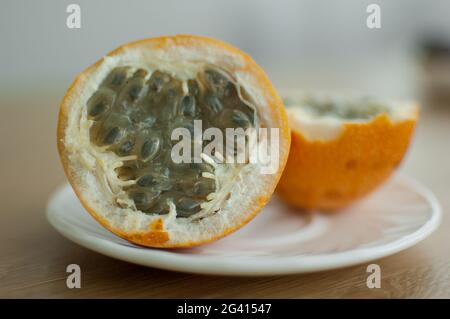 Frische, reife Bio-Granadilla oder gelbe Passionsfrucht, halbiert auf einem Holzbrett. Exotische Früchte, gesunde Ernährung Konzept Stockfoto