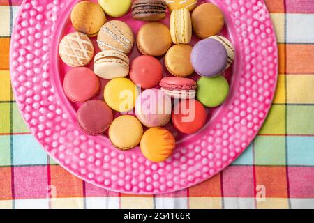 Viele französische Macarons Auswahl an farbenfrohem Gebäck auf rosa Dessertplatte Draufsicht. Retro Vintage Wohnküche Hintergrund. Auswahl an ausgefallenen Gebäckstücken Stockfoto