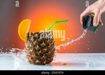 Backstage-Aufnahmen von verschütteter Flüssigkeit. Machen Sie ein Cocktail-Spray. Hinter der Szene eines kommerziellen Shootings. Spritzer Wasser über die Ananas. Stockfoto