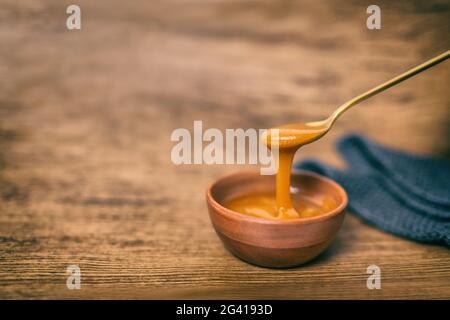 Manuka Honig rohe organische Flüssigkeit aus Manuka Blumen in Neuseeland. Gesunde antibakterielle antimykotische Eigenschaft Blume. Auf braunem Holzhintergrund Stockfoto