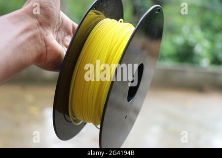Filamente, die im 3d-Drucker auf einer in der Hand gehaltenen Spule verwendet werden. Stockfoto