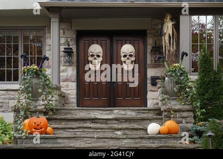 Haustüren mit Halloween Totenkopf Dekorationen und Kürbissen Stockfoto