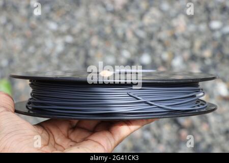 Druckerfilament in einer Spule, die für kreative Projekte auf einem 3D-Drucker in der Hand gehalten wird. Stockfoto