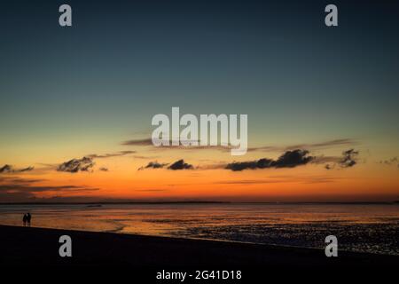 Silhouette von zwei Menschen am Wattenmeer in der Abenddämmerung, Schilig, Wangerland, Friesland, Niedersachsen, Deutschland, Europa Stockfoto