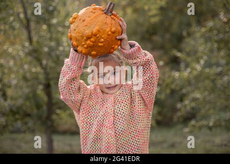Deformierte hässliche orange Kürbis in einem Kind Hände. Stockfoto