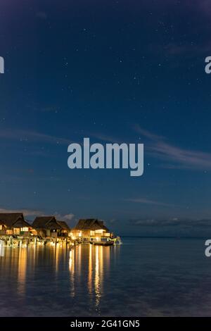 Überwasserbungalows des Sofitel Ia Ora Beach Resort in der Lagune von Moorea mit dem Kreuz des Südens am Sternenhimmel in der Nacht, Moorea, Windward is Stockfoto