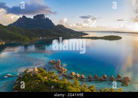 Luftaufnahme des Sofitel Bora Bora Private Island Resort mit Überwasser-Bungalows in der Lagune von Bora Bora mit Mount Otemanu bei Sonnenaufgang, Vaitape, Bora Bora, Stockfoto