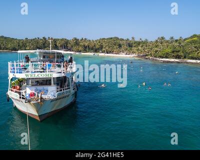 Luftaufnahme von John's Tours No. 9 Ausflugsboot und Touristen schnorcheln in klarem Wasser in der Nähe von Strand mit Kokospalmen, May Rut Island, in der Nähe von Phu Quoc I Stockfoto