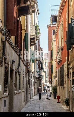 Menschen zu Fuß entlang einer schmalen Straße in Venedig Stockfoto