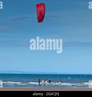 Portobello, Edinburgh, Schottland, UK Wetter. Juni 2021. Guter Wind zum Kitesurfen auf dem Firth of Forth. Temperatur von 14 Grad Celsius.im Bild: Vier junge Damen, die dem Kitesurfer nah und persönlich kommen. Stockfoto