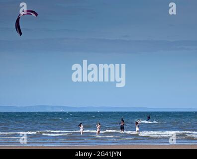 Portobello, Edinburgh, Schottland, UK Wetter. Juni 2021. Guter Wind zum Kitesurfen auf dem Firth of Forth. Temperatur von 14 Grad Celsius.im Bild: Vier junge Damen, die dem Kitesurfer nah und persönlich kommen. Stockfoto