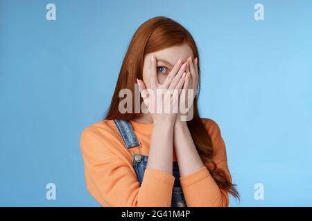 Kein Peeking Versprechen. Charmant fasziniert niedlich Rotschopf Teenager-Mädchen versteckt Gesicht decken Augen Handflächen durch die Finger schauen Sie sich gi Stockfoto