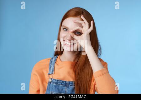 Mädchen suchen Perfektion. Charmante ziemlich froh Rothaarige weibliche Studentin versichert alles ok zeigt okay Zeichen Auge Blick durch SM Stockfoto