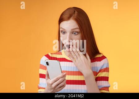 Erstaunt sprachlos junge Teenager Rotschopf Mädchen Student keuchend Tropfen Kiefer sagen omg wow Abdeckung geöffneten Mund Palme schockiert überrascht Stockfoto