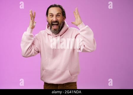 Glücklich aufgeregt glücklich Erwachsenen bärtigen Mann feiert ausgezeichnete Nachrichten heben Hände gestikulieren begeistert lächelnd broaldy triumphierenden vic Stockfoto