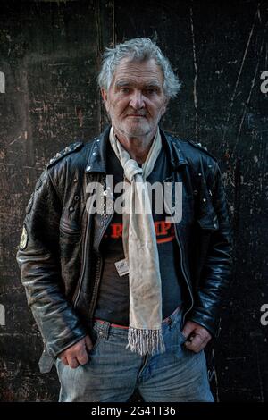 Reifer Rocker mit Lederjacke und weißem Schal in London, England. Stockfoto