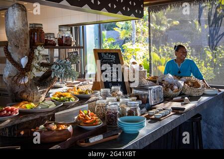 Lächelnde Kellnerin hinter einem fantastischen Frühstücksbuffet im Tovolea Restaurant des Six Senses Fiji Resort, Malolo Island, Mamanuca Group, Fiji Isla Stockfoto