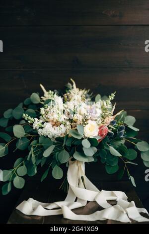 Brautstrauß aus weißen und cremefarbenen Rosen, Ästen von Eukalyptusbäumen, Delphinium und weißen Bändern Stockfoto