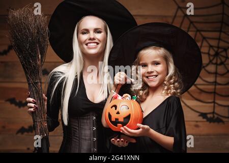 Halloween-Konzept - schöne kaukasische Mutter und ihre Tochter in Hexenkostümen feiern Halloween mit Teilen Halloween c Stockfoto