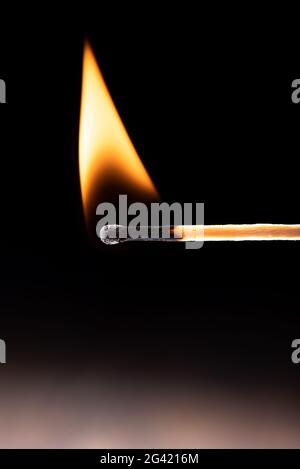 Dreieckige Flamme auf einem brennenden Streichholz vor schwarzem Hintergrund. Nahaufnahme. Speicherplatz kopieren. Stockfoto