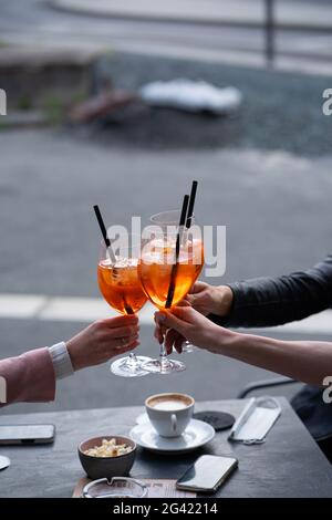 Mädchen, die Spaß haben, jubeln und kalte Getränke trinken, Freundschaften in der Bar im Freien genießen, Nahaufnahme auf den Händen Stockfoto