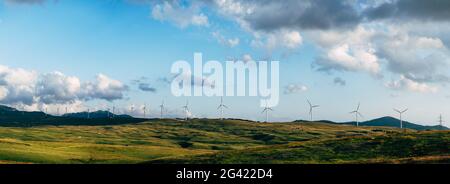 Panorama von vielen riesigen Windturbinen am Horizont mit blauem Himmel und Wolken. Umweltfreundliches Technologiekonzept. Industriewind weit entfernt Stockfoto