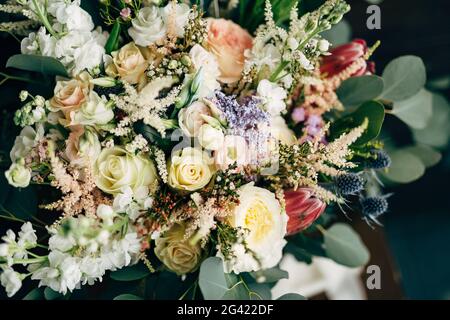 Brautstrauß aus weißen und cremefarbenen Rosen, Ästen von Eukalyptusbäumen, protea, Eryngium und Delphinium Stockfoto