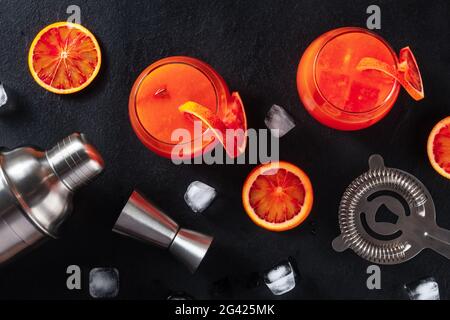 Orangefarbene Cocktails mit Baraccessoires, Overhead-Shot auf schwarzem Hintergrund Stockfoto