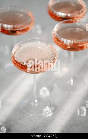 Gläser mit kaltem rosafarbenem Champagner auf dem Tisch in der Nähe von Eiswürfeln Stockfoto