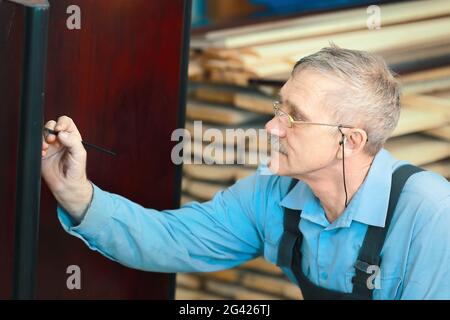 Porträt eines älteren Zimmermanns bei der Arbeit in einer Schreinerei. Stockfoto