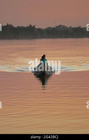 Gambia; Central River Region; Nachglühen auf dem Gambia River bei Kuntaur; zwei Männer in einem Boot Stockfoto
