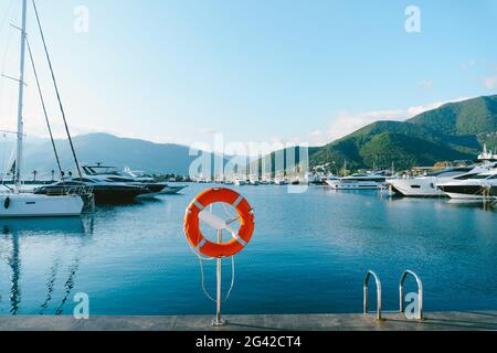 Orange Rettungsboje auf Chrombasis, am Yachthafen in Porto Montenegro, einem Elitegebiet in Montenegro, der Stadt Tivat. Stockfoto