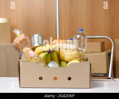 Karton mit verschiedenen Produkten, Obst, Nudeln, Sonnenblumenöl in einer Plastikflasche und Konservierung Stockfoto