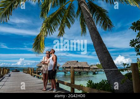 Junges Paar auf der Promenade zu den Überwasser-Bungalows im Sofitel Bora Bora Private Island Resort, Bora Bora, Leeward Islands, Französisch-Polynesien, South Pacif Stockfoto