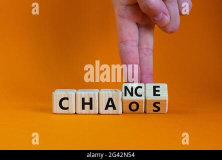 Symbol für Zufall oder Chaos. Geschäftsmann dreht Holzwürfel und ändert das Wort „Chaos“ in „Zufall“. Schöner orangefarbener Tisch, orangefarbener Hintergrund, Kopierbereich Stockfoto